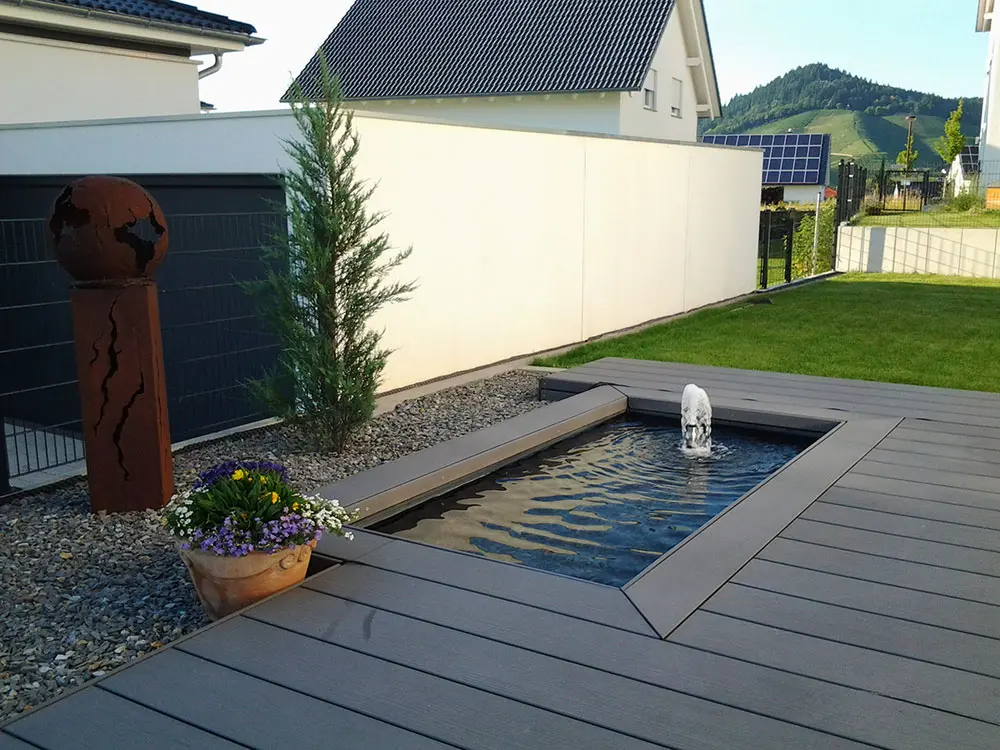 WPC-Terrasse mit eingefasstem Teichbecken und Fontäne Wasserspiel