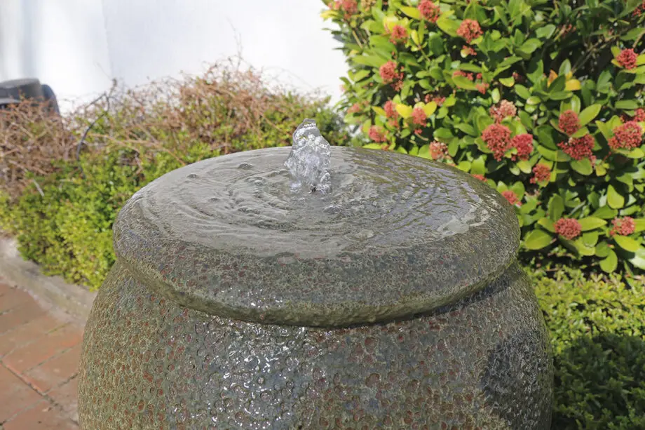 Palermo Keramik-Springbrunnen mit Schale in antiker Krugform, Wasser fließt in die Schale, aufgestellt auf einer Terrasse mit roten Pflastersteinen.