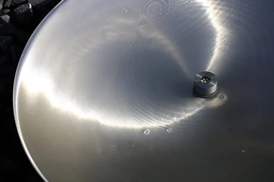 Edelstahl-Wasserschale Modell 2396 mit leicht gewellter Wasseroberfläche, aufgestellt auf einer Terrasse mit dunklen Steinplatten, umgeben von modernen Pflanzen.