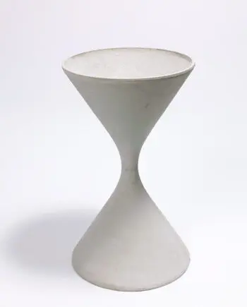 Swisspearl Spindel aus Faserzement in einem minimalistischen Innenraum, bepflanzt mit Sukkulenten, neben einer modernen Einrichtung.