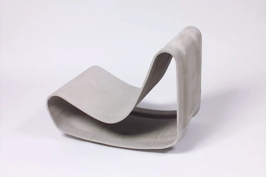 Guhl Sessel (Loop Chair) aus Faserzement in einem modernen Garten, umgeben von Gräsern und minimalistischer Landschaftsgestaltung.