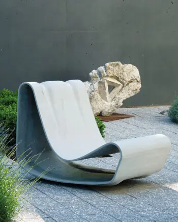 Guhl Sessel (Loop Chair) aus Faserzement in einem modernen Garten, umgeben von Gräsern und minimalistischer Landschaftsgestaltung.