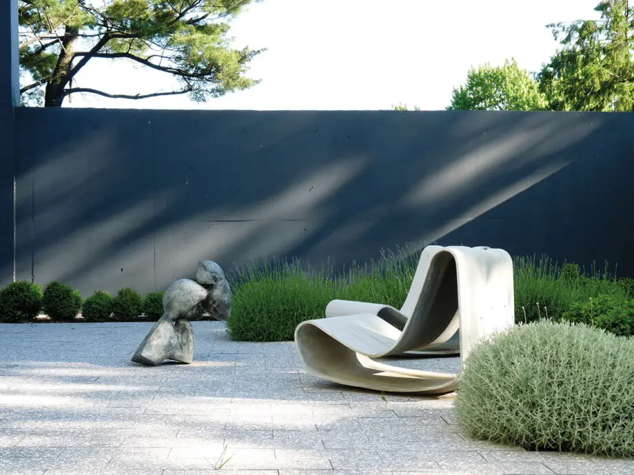 Guhl Sessel (Loop Chair) aus Faserzement in einem modernen Garten, umgeben von Gräsern und minimalistischer Landschaftsgestaltung.