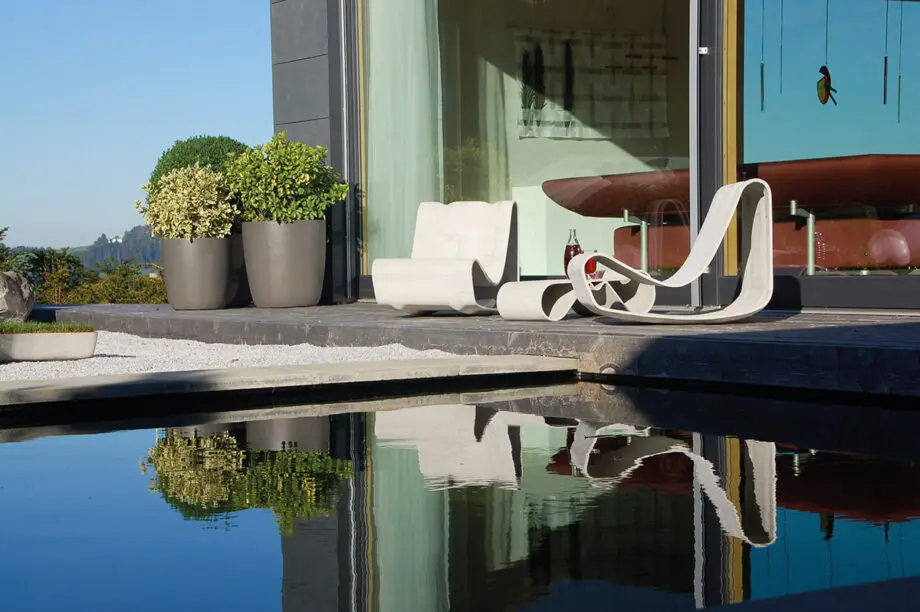 Guhl Sessel (Loop Chair) aus Faserzement in einem modernen Garten, umgeben von Gräsern und minimalistischer Landschaftsgestaltung.