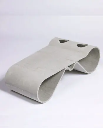 Guhl Tisch aus Faserzement in einem modernen Garten neben einem Guhl Sessel, umgeben von Kies und minimalistischer Bepflanzung.
