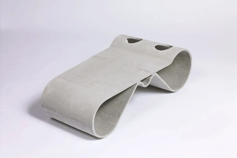Guhl Tisch aus Faserzement in einem modernen Garten neben einem Guhl Sessel, umgeben von Kies und minimalistischer Bepflanzung.