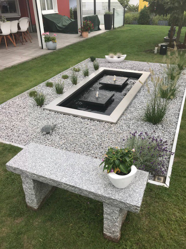 Rechteckiges Wasserbecken mit Edelstahlrand und kleinem Wasserspiel