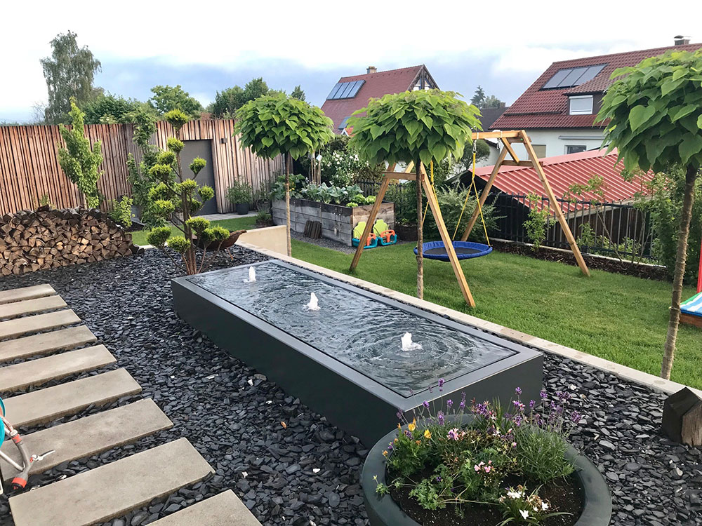 Rechteckiges Wasserbecken mit Edelstahlrand und kleinem Wasserspiel